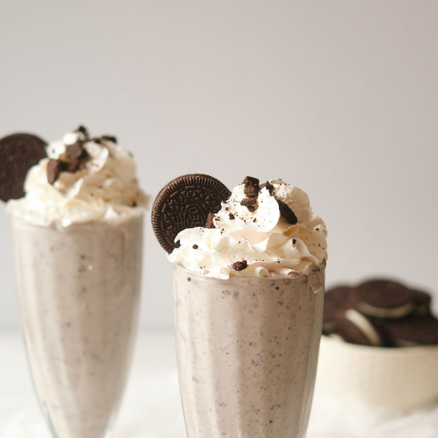 Creamy Oreo milkshake in a glass garnished with whipped cream and Oreo cookies