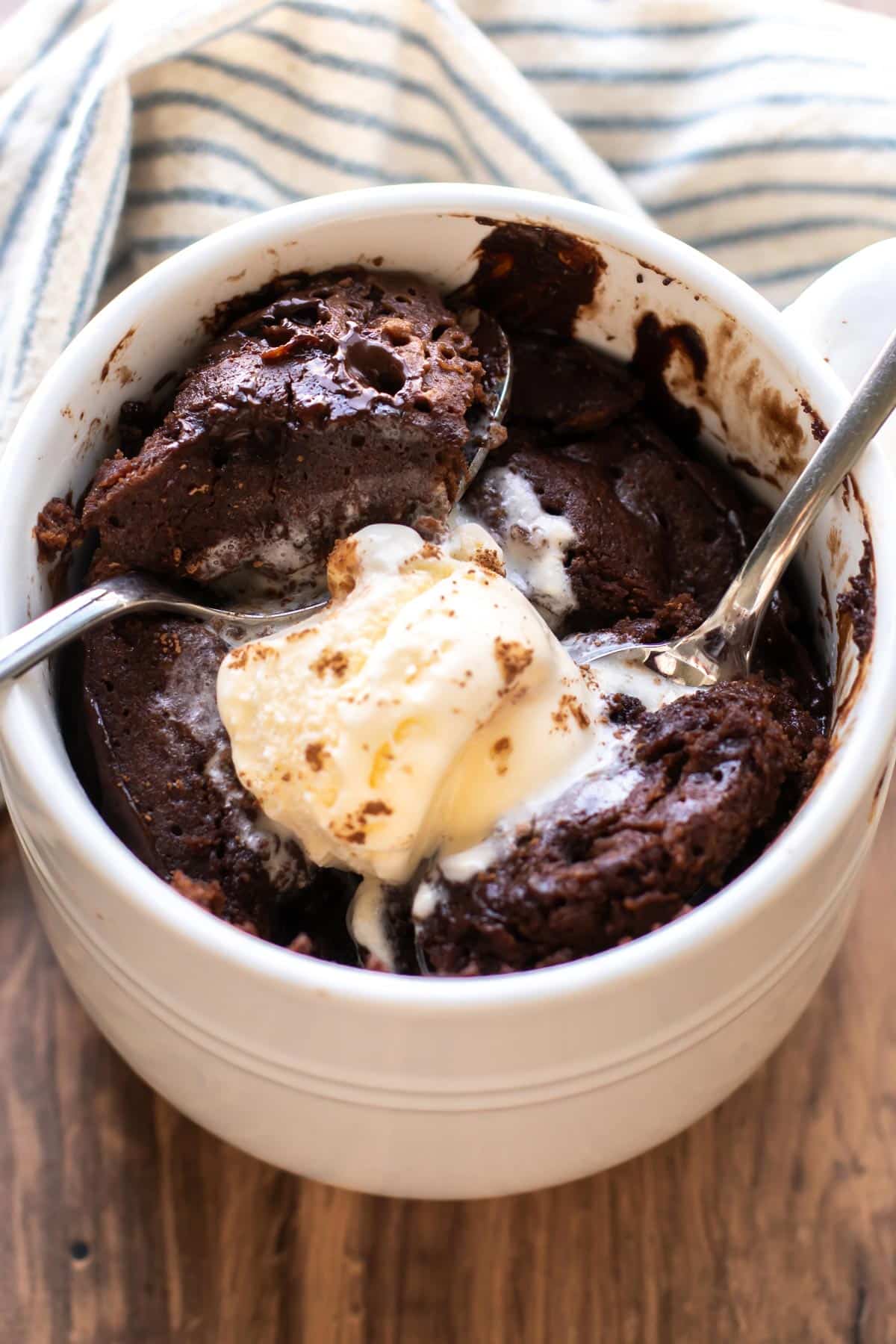 Fluffy chocolate mug cake with powdered sugar and vanilla ice cream